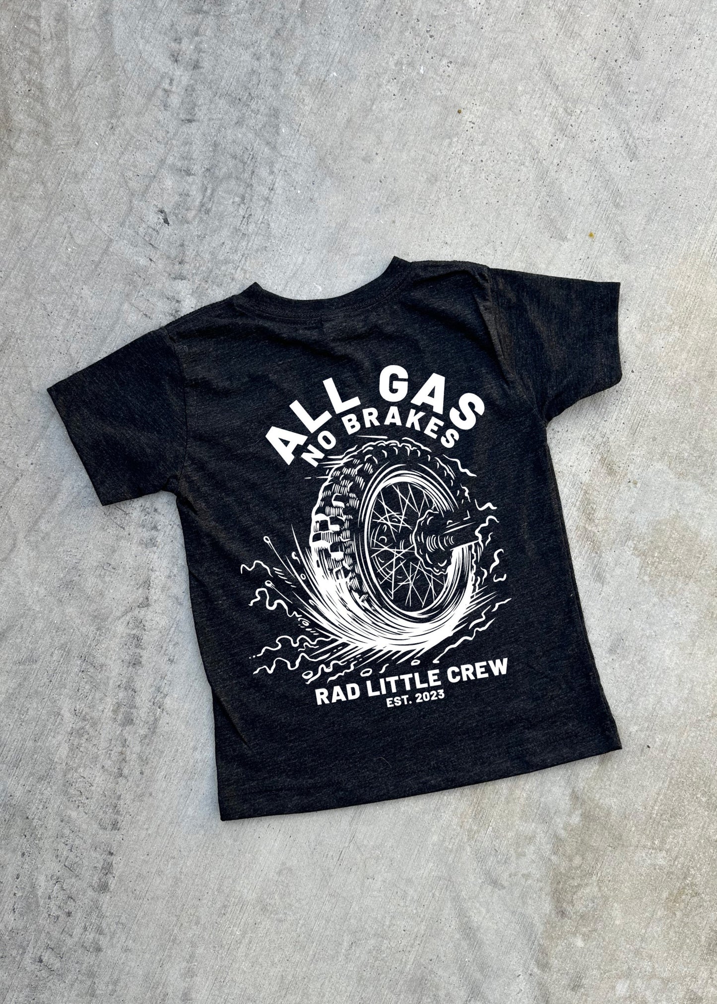 Black t-shirt with white graphic and text on a gray concrete surface